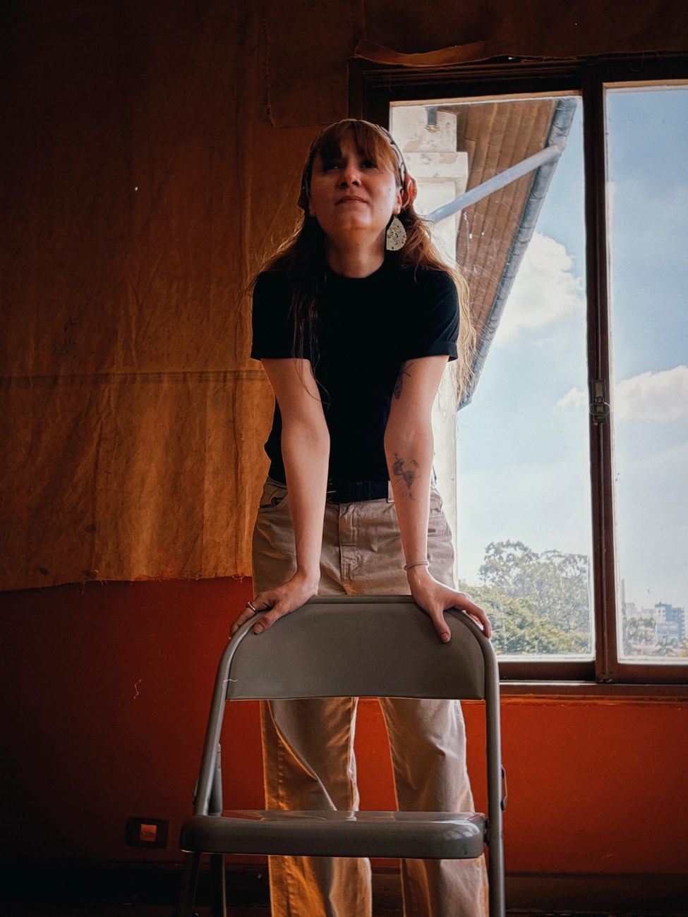 Atriz apoiada numa cadeira em cena